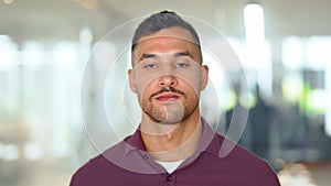 Confident young Latin business man standing in office, close up portrait.