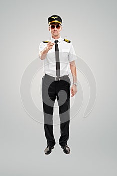 Confident young male pilot pointing at camera against gray background