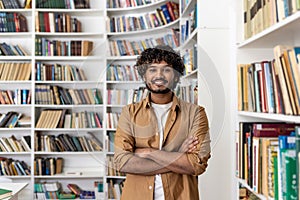 Confident young man with arms crossed standing in a library