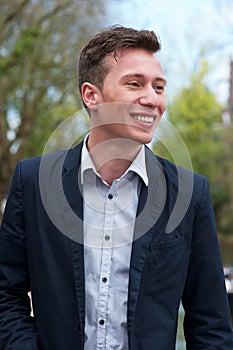 Confident young man in blue jacket, smiling outdoors