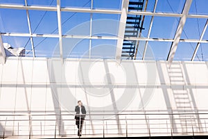 Confident young man in full suit while standing modern office hall