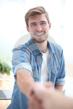 Confident young man holding out his hand for a handshake