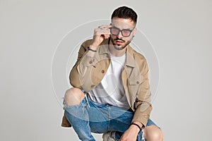 Confident young man in jacket fixing sunglasses