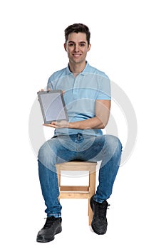 Confident young man presenting his blank tablet and smilin