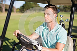 Confident young man sitting in golf buggy
