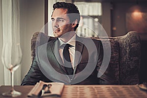 Confident young man sitting in restaurant waiting for somebody