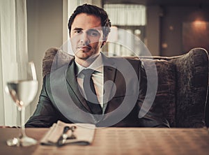 Confident young man sitting in restaurant waiting for somebody