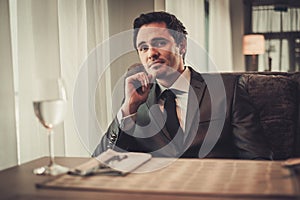 Confident young man sitting in restaurant waiting for somebody