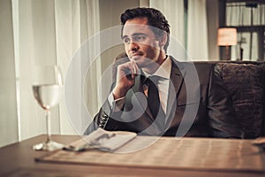 Confident young man sitting in restaurant waiting for somebody.