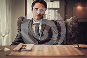 Confident young man sitting in restaurant waiting for somebody.