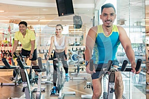 Confident young man smiling during indoor cycling class in a modern fitness club