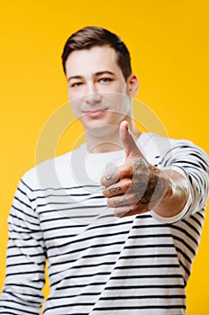 Confident young man in a striped black and white shirt showing thumbs up