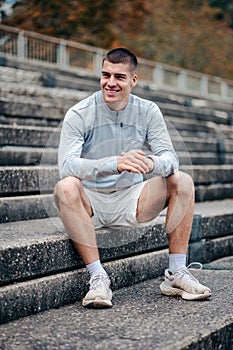 Confident young man in workout clothes sitting on a set of stairsteps