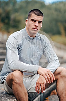 Confident young man in workout clothes sitting on a set of stairsteps