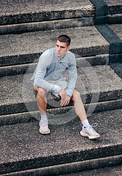 Confident young man in workout clothes sitting on a set of stairsteps