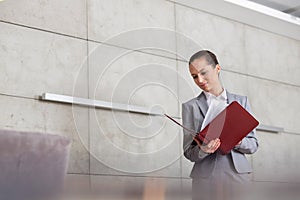 Confident young saleswoman examining documents while standing in apartment