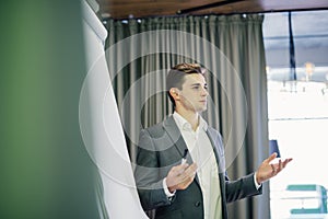 Confident young team leader or manager standing in front of a flip chart and present project on office