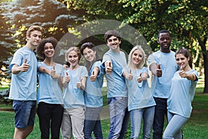 Confident young volunteers gesturing thumbs up at park