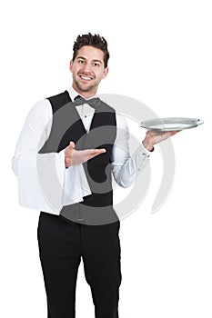 Confident young waiter with napkin and serving tray