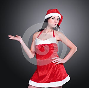 Confident young woman in costume of Santa Claus showing to copy