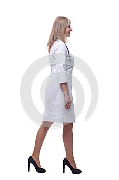 confident young woman doctor striding forward . isolated on a white background.