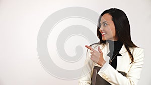 Confident young woman holding a file pointing towards her right for copy space