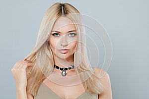 Confident young woman with make-up and long blonde hair against white studio wall background