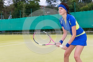 Confident young woman playing tennis on tennis court