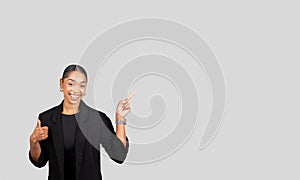 A confident young woman in professional attire gestures with her hand, giving a thumbs up