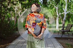 Confident young woman professional with a laptop in a vibrant city park