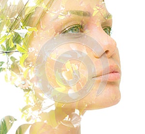A confident young woman`s double exposure portrait with green tree leaves close up against white bakcground