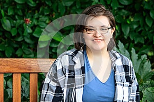 Confident young woman with short hair in her 20`s sitting outside on bench