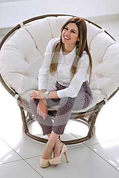 Confident young woman sitting in a soft round chair