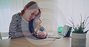 Confident young woman using stylus for writing on digital tablet