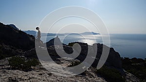 Confident Young woman walks uphill towards the summit at sunrise in Slow motion. Silhouette of a Lady hiking in