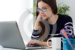 Confident young woman working in her office with laptop.