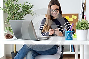 Confident young woman working in her office with mobile phone.