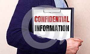 CONFIDENTIAL INFORMATION is written on a white sheet held by a man standing sideways