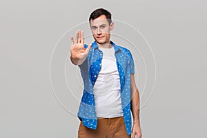 Confindent handsome man in a white tee and blue shirt showing Stop gesture