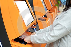 Confirm flight details. Close-up female hands is using self-service check-in kiosk while standing at international airport