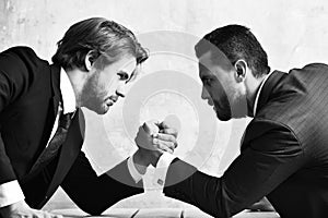 Conflict. Businessmen arm wrestling in suit in office.