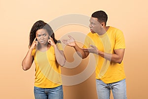 Conflict, family relationship problems. Angry black man screaming at wife, mad woman covering ears with hands