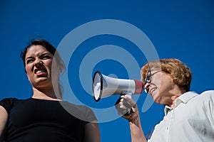 The conflict of generations. An emotional elderly woman shouting at her daughter in a megaphone. An elderly mother