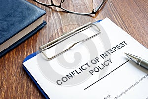 Conflict of interest policy and pen on  wooden surface