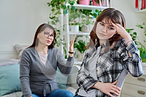 Conflict between mother and teen daughter, offended teenage girl sitting with back