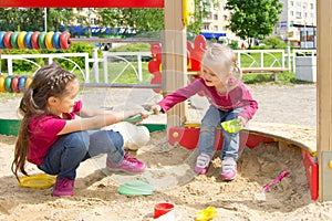 Conflict on the playground. Two kids fighting over a toy shovel in the sandbox