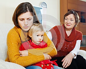 Conflict between sad woman with baby and mature mother