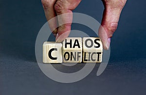 From conflict to chaos symbol. Concept words Conflict and Chaos on wooden cubes. Businessman hand. Beautiful grey background.