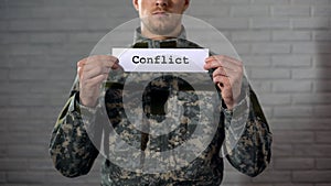 Conflict word written on sign in hands of soldier, military annexation, war