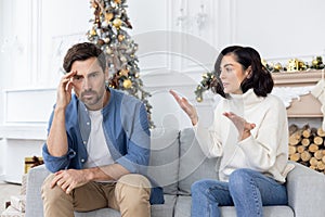 Conflict of a young couple, family on New Year& x27;s holidays. A young man and a woman are sitting on the couch and
